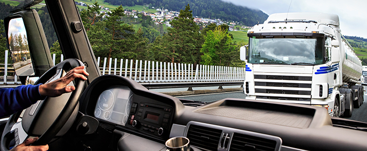 a truck is visible from another trucks interior front windshield in a clean environment